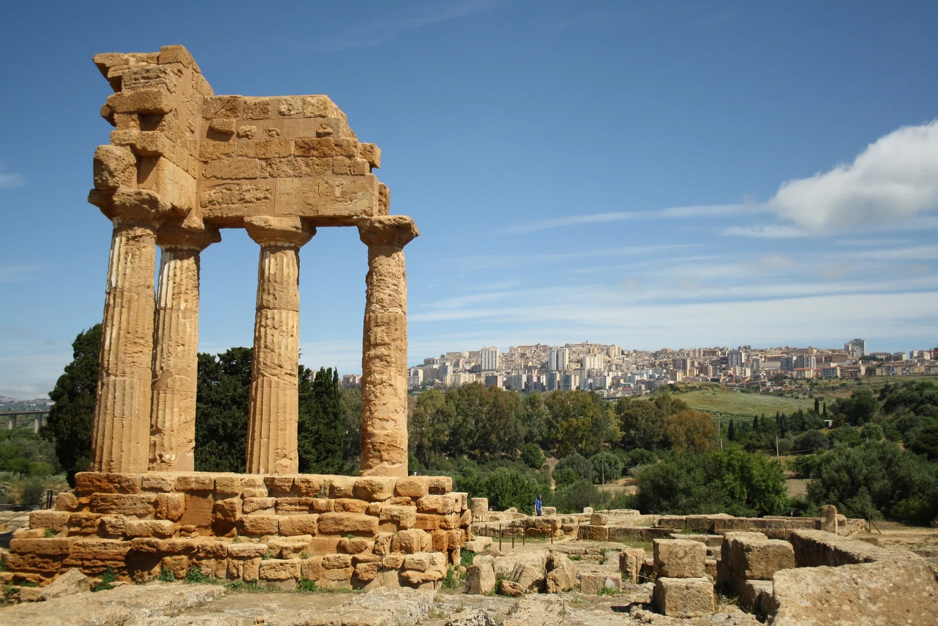 Rovine del Tempio dei Dioscuri nella Valle dei Templi ad Agrigento, con vista sulla città sullo sfondo