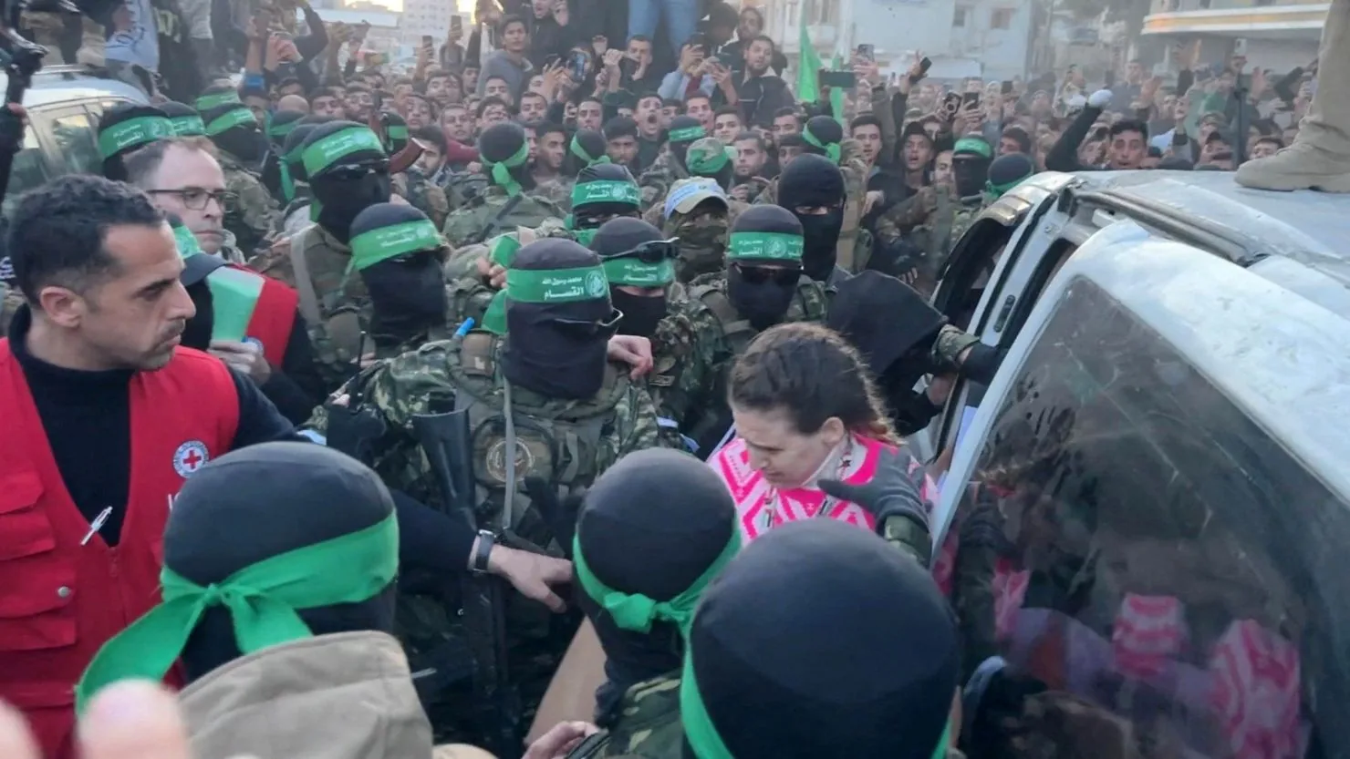 Ostaggi israeliani circondati da miliziani di Hamas durante una fase di rilascio a Gaza, tra folla e tensione.