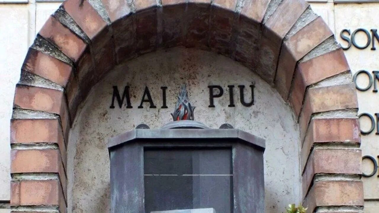 Ingresso di un memoriale con la scritta "MAI PIÙ" scolpita in un arco di mattoni, simbolo del ricordo della Shoah.
