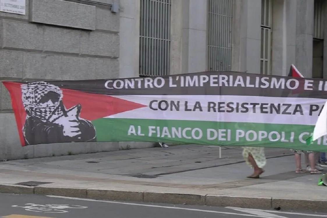 Striscione di protesta con bandiera palestinese e slogan contro l’imperialismo e a sostegno della resistenza popolare, esposto in una manifestazione.