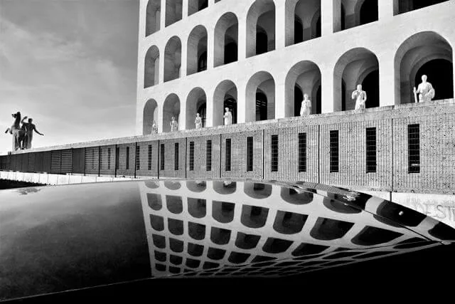 Palazzo della Civiltà Italiana all’EUR, simbolo dell’architettura razionalista a Roma, riflesso in una superficie d'acqua.