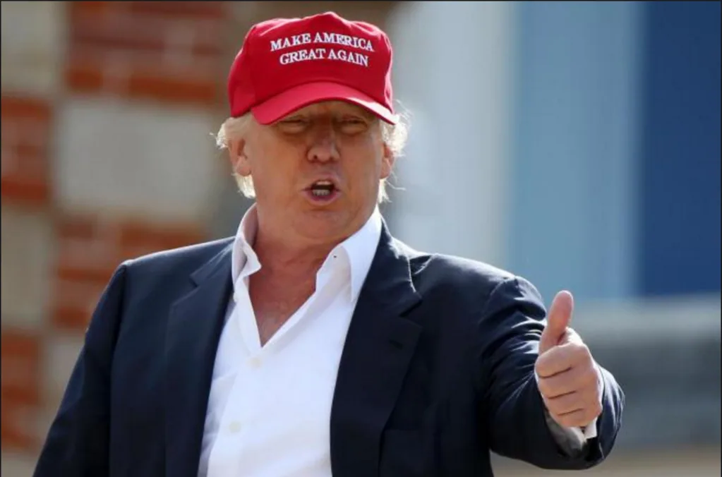 Donald Trump con cappellino rosso Make America Great Again durante evento pubblico, simbolo della narrativa trumpiana negli USA