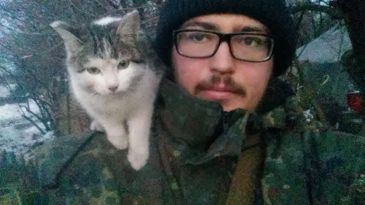 Nazar Rozlutsky, intellettuale ucraino al fronte, in mimetica con un gatto sulla spalla: resistenza e umanità in trincea.