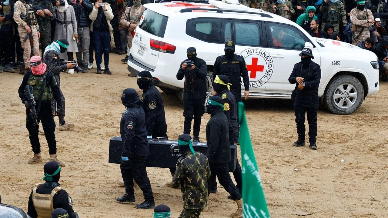 Miliziani di Hamas in parata con veicolo Croce Rossa sullo sfondo: simbolo delle ambiguità nel conflitto israelo-palestinese.