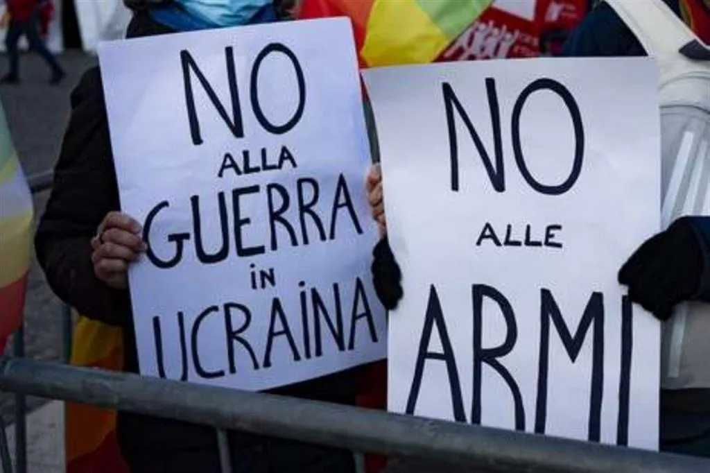 Manifestanti con cartelli “No alla guerra in Ucraina” e “No alle armi” durante protesta pacifista