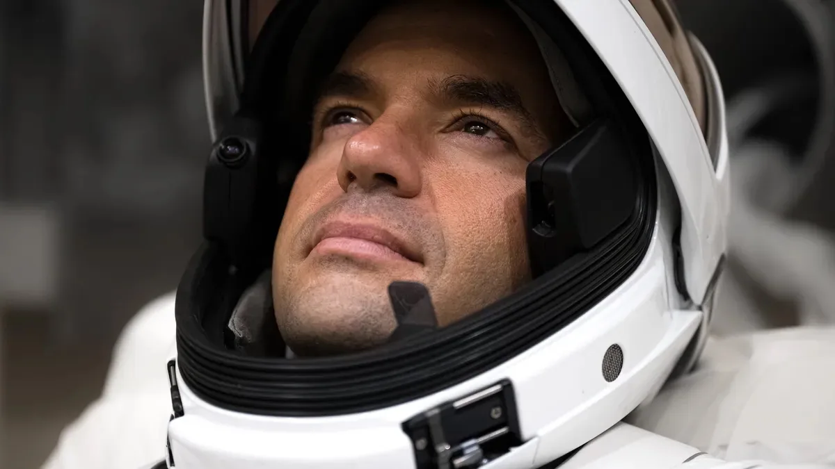 Astronauta in tuta spaziale moderna guarda verso l’alto, simbolo della nuova corsa alla Luna guidata da USA e SpaceX.